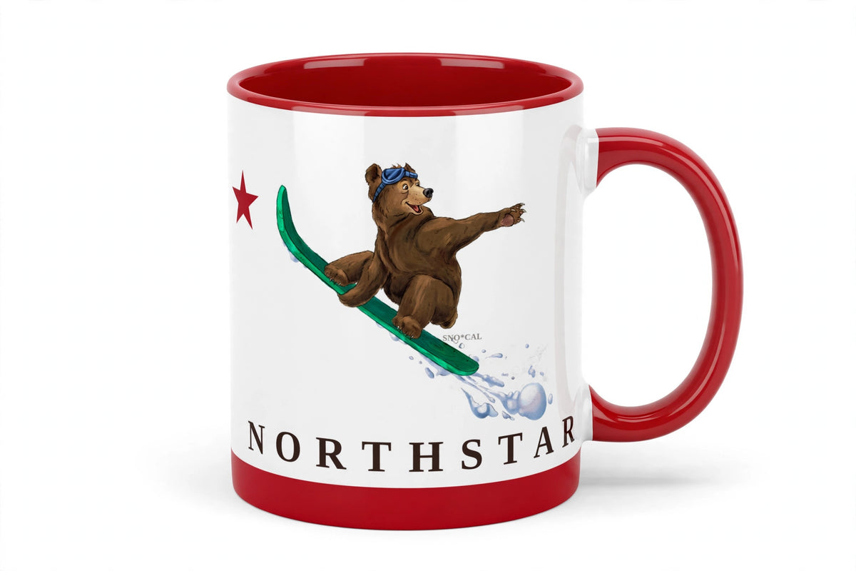 White ceramic mug with red rim handle and inside with Northstar CA flag design, grizzly bear catching air on a snowboard, front view